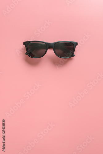 Black stylish sunglasses on pink background. Flat lay. Minimal style concept