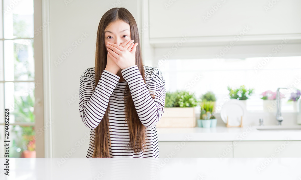 Beautiful Asian woman wearing stripes sweater shocked covering mouth with hands for mistake. Secret concept. Beautiful Asian woman wearing stripes sweater shocked covering mouth with hands for mistake. Secret concept.
