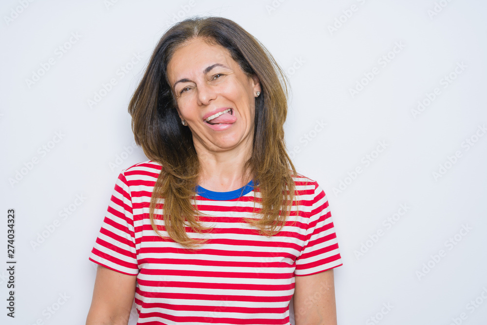 Middle age senior woman standing over white isolated background sticking tongue out happy with funny expression. Emotion concept. Middle age senior woman standing over white isolated background sticking tongue out happy with funny expression. Emotion concept.