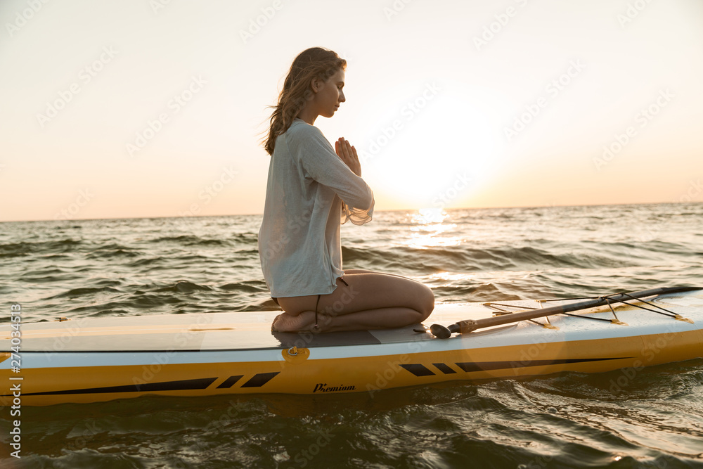 Beautiful young woman sitting on a stand up paddle board