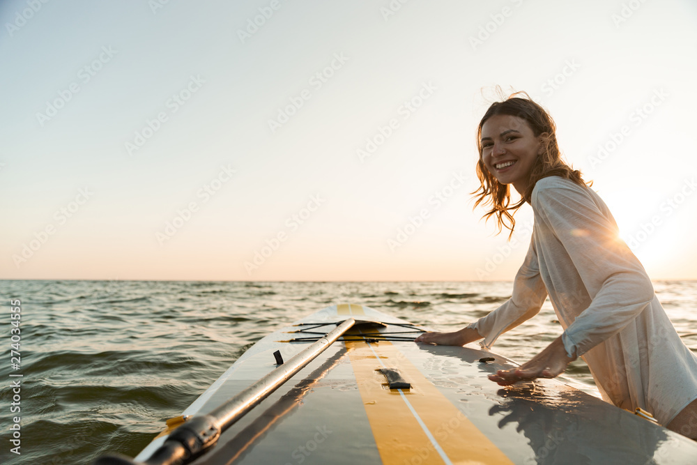 Beautiful smiling young woman using a stand up paddle board - obrazy, fototapety, plakaty 