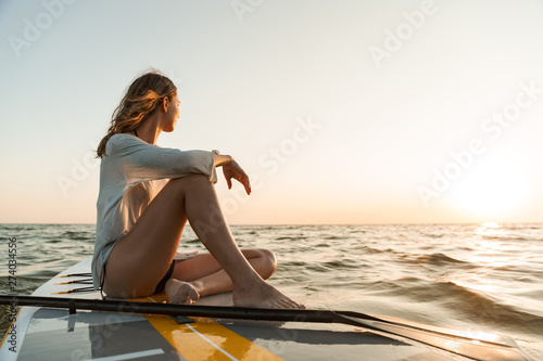 Beautiful young woman sitting on a stand up paddle board photo