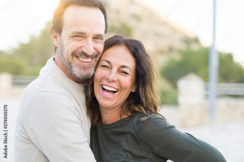 Romantic couple smiling and cuddling on a sunny day - obrazy, fototapety, plakaty 