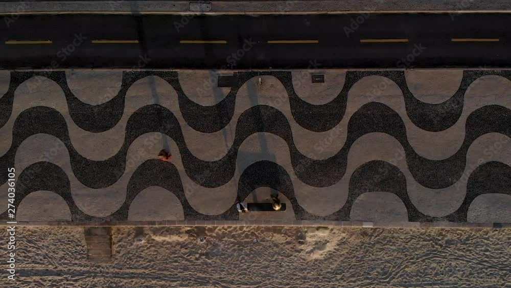 Sideways aerial panning showing the patterns in the sidewalk pavement, bicycle lane and beach of Copacabana at sunrise. 60fps footage at normal speed. Sideways aerial panning showing the patterns in the sidewalk pavement, bicycle lane and beach of Copacabana at sunrise. 60fps footage at normal speed.