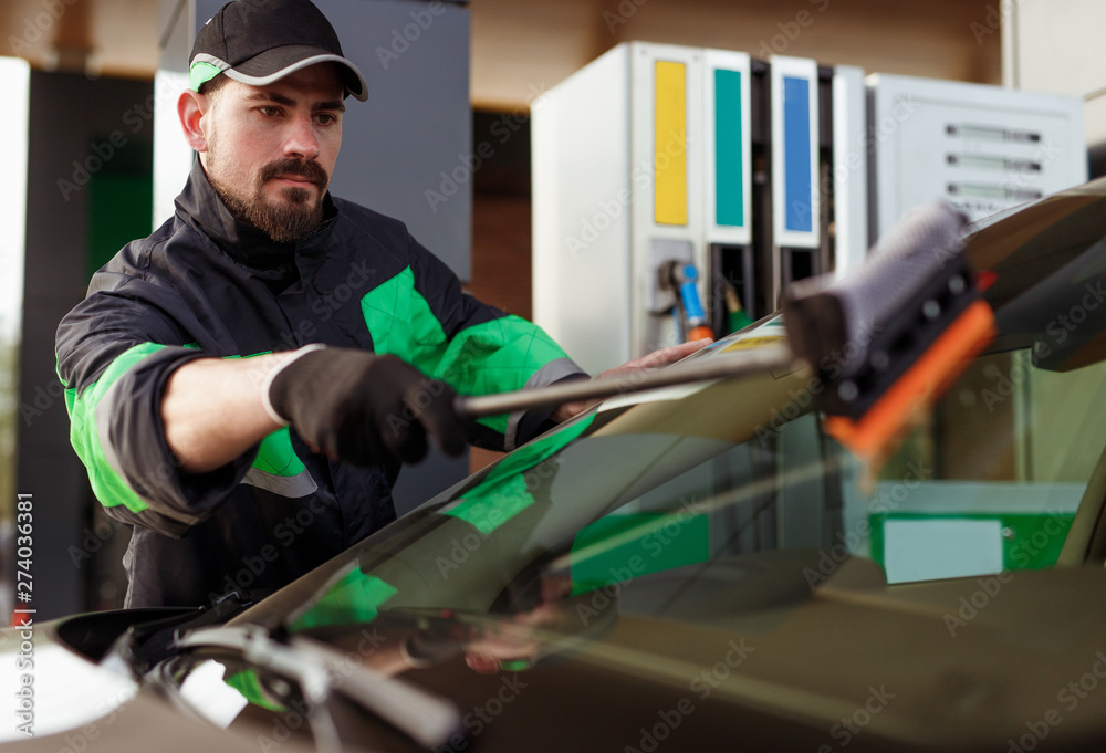 Bearded man washing windshield on gas station Bearded man washing windshield on gas station