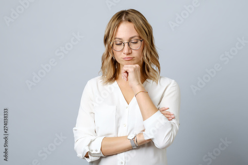 Portrait of pensive young woman standing isolated