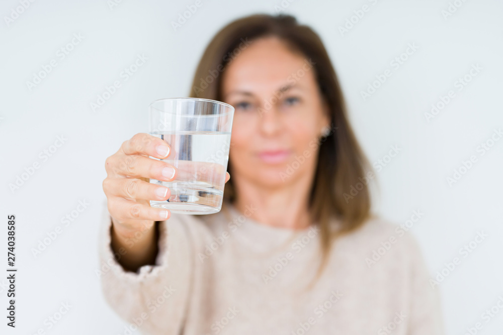 Middle age woman drinking glass of water isolated background with a confident expression on smart face thinking serious Middle age woman drinking glass of water isolated background with a confident expression on smart face thinking serious