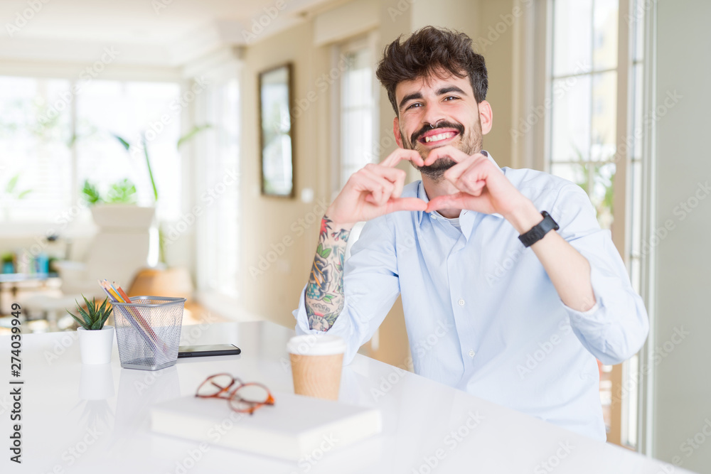 Young business man working smiling in love showing heart symbol and shape with hands. Romantic concept.