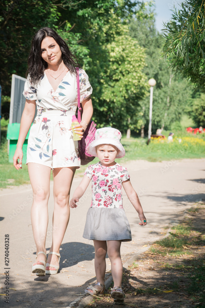 happy family concept beautiful mother and little daughter are walking in the city park in the summer