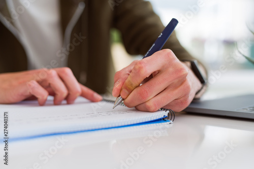 Close up of man hands writing on notebook, working taking notes