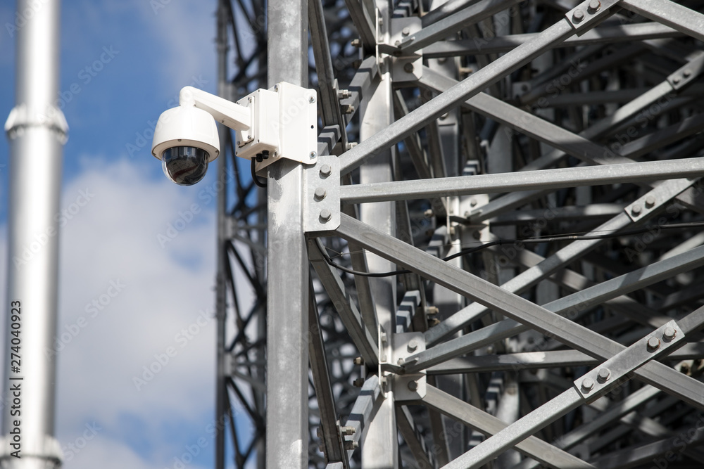 View of a contemporary surveillance video cam attached to a metal girder of the facade of a modern business skyscraper; security video camera on the frontage of an office high-rise 