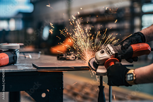 Grinding metal part at factory workshop, close-up. photo