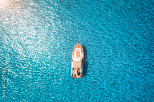 Aerial view of luxury yacht in transparent blue sea at sunset in summer in Mallorca, Spain. Colorful landscape with boat, bay, clear azure water. Top view from air. Travel. Seascape with motorboat © den-belitsky