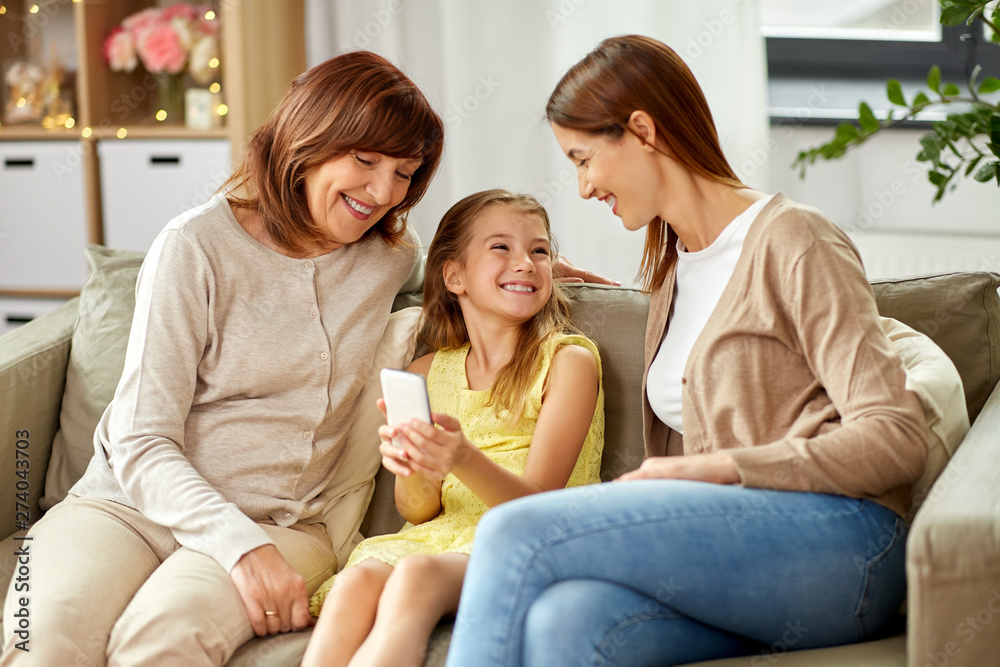 family, generation and technology concept - happy mother, daughter and grandmother with smartphone at home