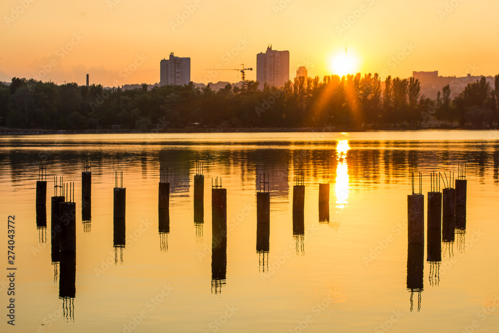 City at sunset near the water and piles