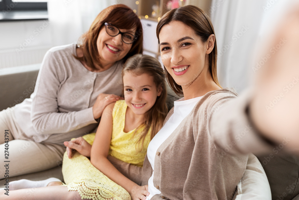 family, generation and technology concept - happy mother, daughter and grandmother taking selfie by smartphone at home family, generation and technology concept - happy mother, daughter and grandmother taking selfie by smartphone at home