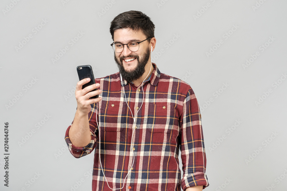 Young cheerful guy in headphones smiling holding phone listening to music Young cheerful guy in headphones smiling holding phone listening to music