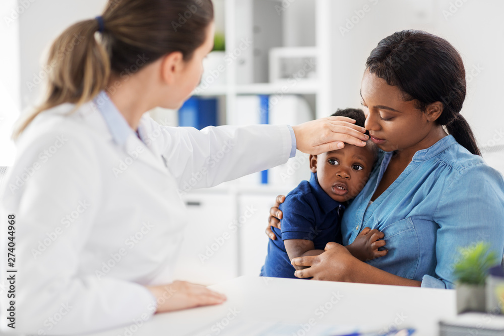 medicine, healthcare and pediatry concept - african american mother with sick son and caucasian doctor measuring baby's temperature by hand at clinic medicine, healthcare and pediatry concept - african american mother with sick son and caucasian doctor measuring baby's temperature by hand at clinic