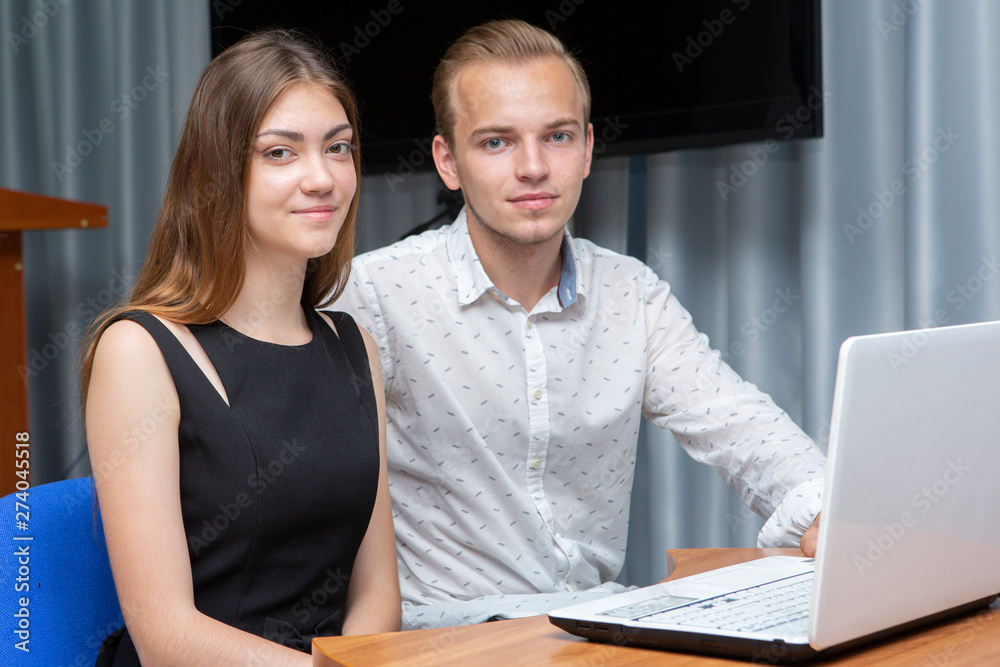 Group of two young euphoric students watching exam results in a laptop in a table Group of two young euphoric students watching exam results in a laptop in a table