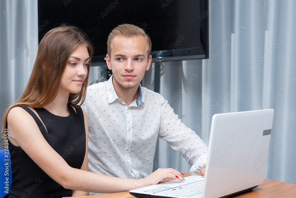 Group of two young euphoric students watching exam results in a laptop in a table Group of two young euphoric students watching exam results in a laptop in a table