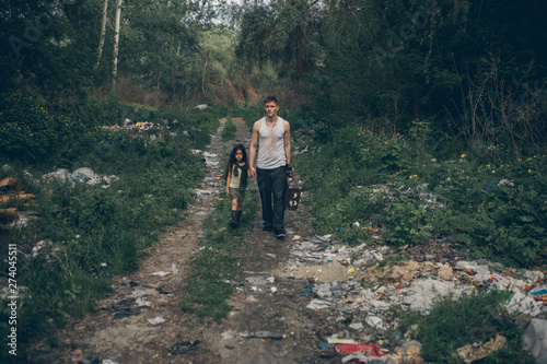 Homeless father and daughter walk through the garbage dump. © Stanislav