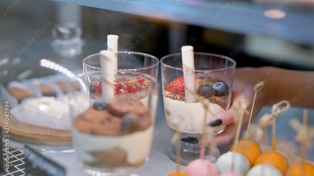woman is taking sweet desserts with fresh berries in a glasses from candy bar in a kitchen of restaurant woman is taking sweet desserts with fresh berries in a glasses from candy bar in a kitchen of restaurant