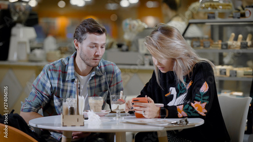 Portrait of a lovely couple in cafe  boyfriend and girlfriend on a date in cozy cafe eating desserts and drinking coffee.