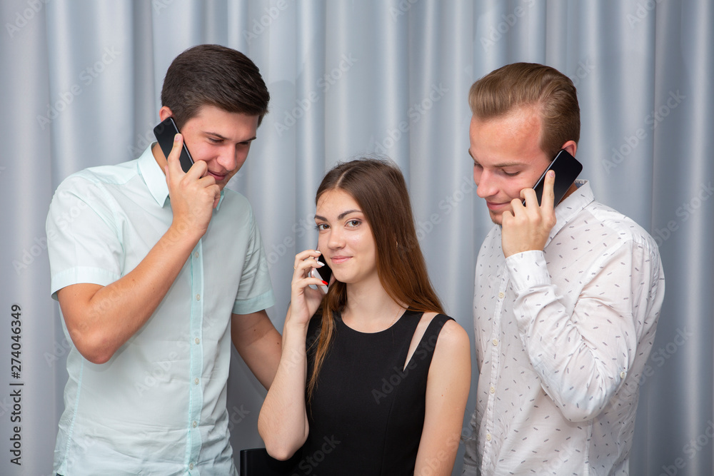 Three young friends standing outdoors and looking at mobile phone.