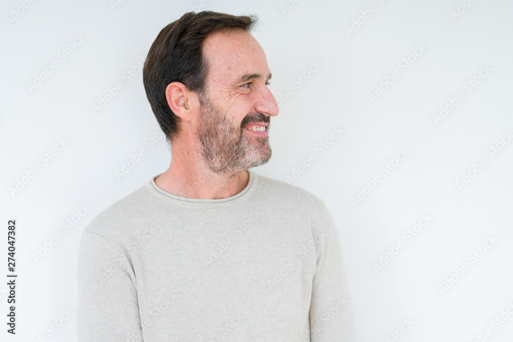 Obraz premium Elegant senior man over isolated background looking away to side with smile on face, natural expression. Laughing confident.