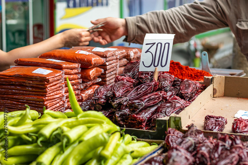 Different types of green and red peppers on the marketplace in Belgrade. Blurred background of seller and customer hands paying cash