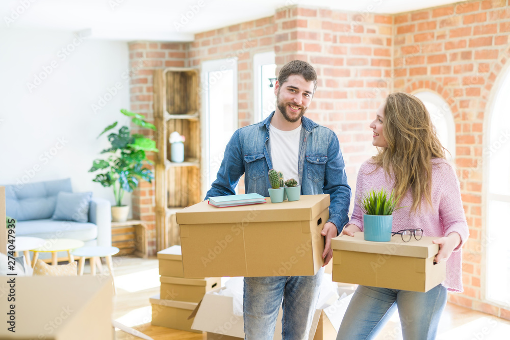 Young beautiful couple very happy together holding cardboard boxes moving to a new home Young beautiful couple very happy together holding cardboard boxes moving to a new home
