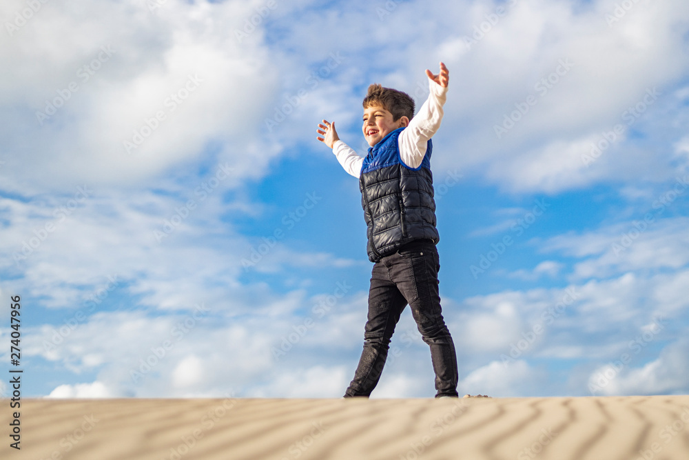 Little boy with arms up on top of a dune Little boy with arms up on top of a dune
