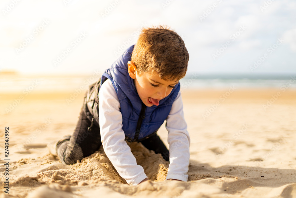 Beautiful boy playing with the sand of a beach