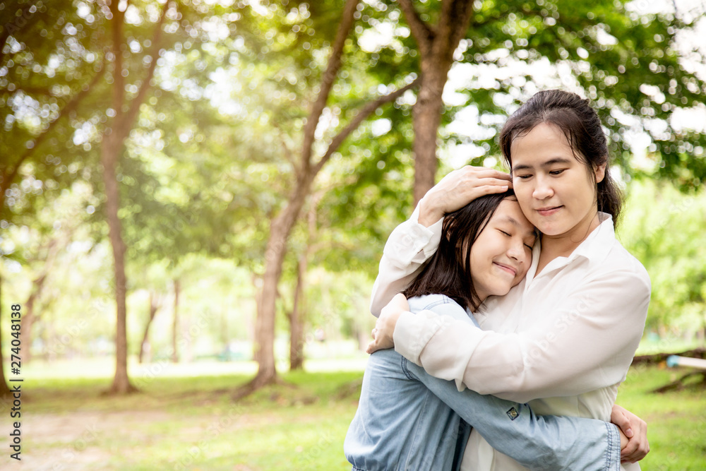 Naklejka premium Happy beautiful asian adult woman and cute child girl with hugging and smiling in summer,love of mother with her little daughter in outdoor park in nature,mother’s day, family, love concept