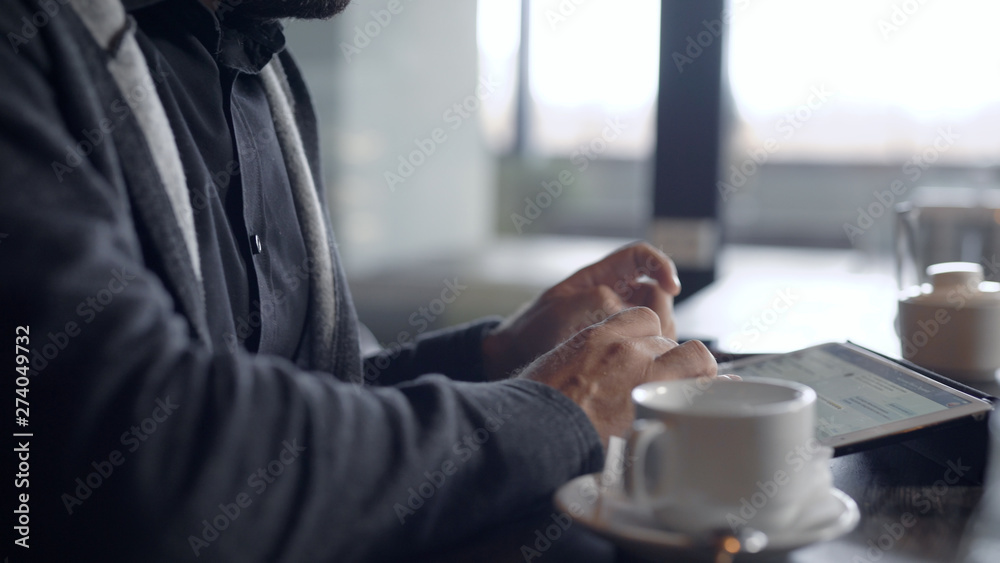 Close-up shot of a guy chatting online on a tablet in cafe, cup of tea on table. Close-up shot of a guy chatting online on a tablet in cafe, cup of tea on table.