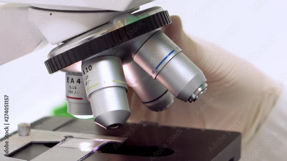 Scientist tune microscope objective lens to get better magnification . Scientist tune microscope objective lens to get better magnification .