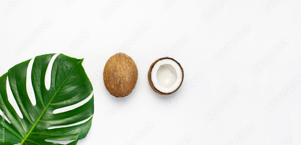 Tropical leaves and fresh coconut on light gray background. Flat lay, top view, copy space. Summer background, nature. Healthy cooking. Creative healthy food concept, half of coconut Tropical leaves and fresh coconut on light gray background. Flat lay, top view, copy space. Summer background, nature. Healthy cooking. Creative healthy food concept, half of coconut