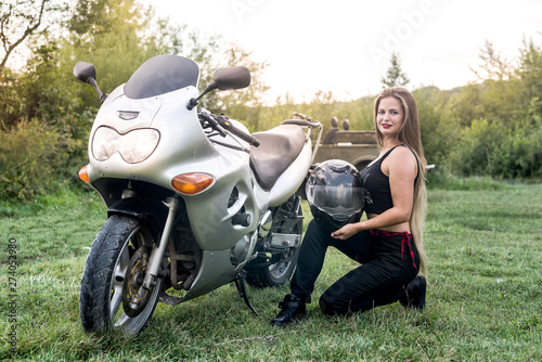Young and happy woman on motorbike posing outdoors