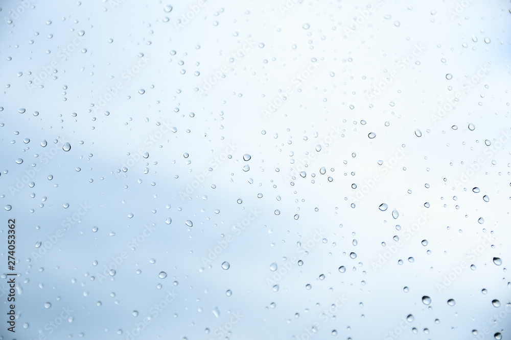  Rain drops on window glasses surface with cloudy grey and green background