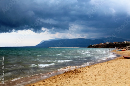 evocative image of rough sea in Sicily with promontory in the background