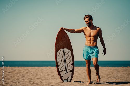 Sticker Young man and woman with a surf board on the beach
