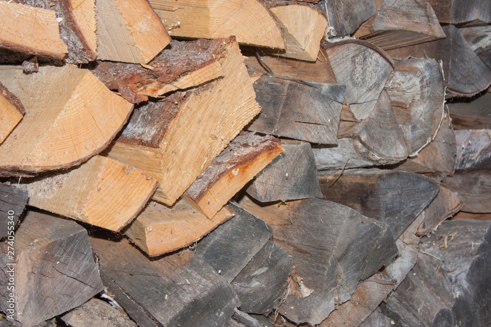 Wood for the village stove or fireplace stacked in a stack. Dry wood texture. Ecologically clean fuel. Selective focus.