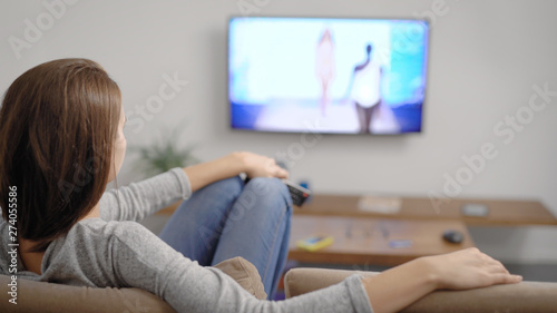 Young woman with glass of drink near TV in room