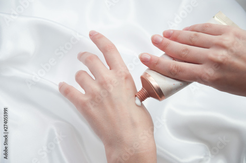 Women s hands apply a nourishing cream on the back of the hand. Hand care concept.