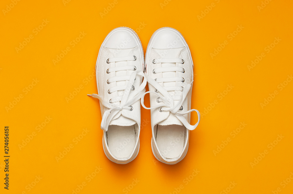 White female fashion sneakers on yellow orange background. Flat lay top view  copy space. Women's shoes. Stylish white sneakers. Fashion blog or magazine  concept. Minimalistic shoe background, sport Stock-foto | Adobe Stock