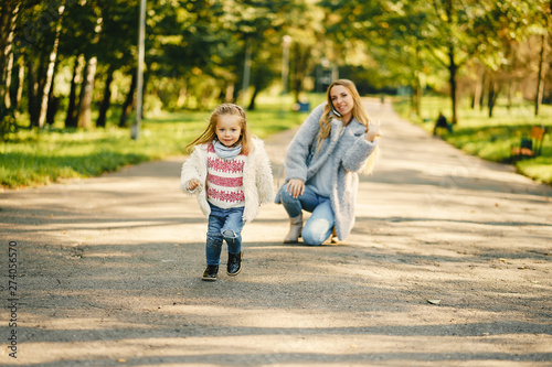 young blonde mother running behind her super energetic toddler daughter in a sunny park