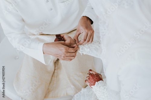 The groom put the wedding bracelet to the bride during solemnization ceremony