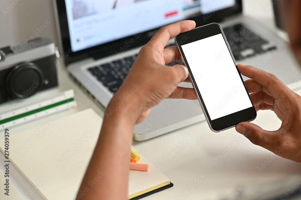 Male using mockup smartphone on desk. Male using mockup smartphone on desk.