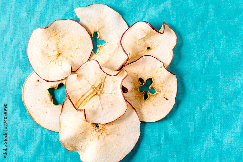 Fototapeta premium Dried apple chips over aqua background with copy space.