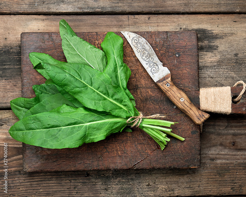 Tablou pe pânză bunch of fresh green sorrel leaves and old brown cutting board